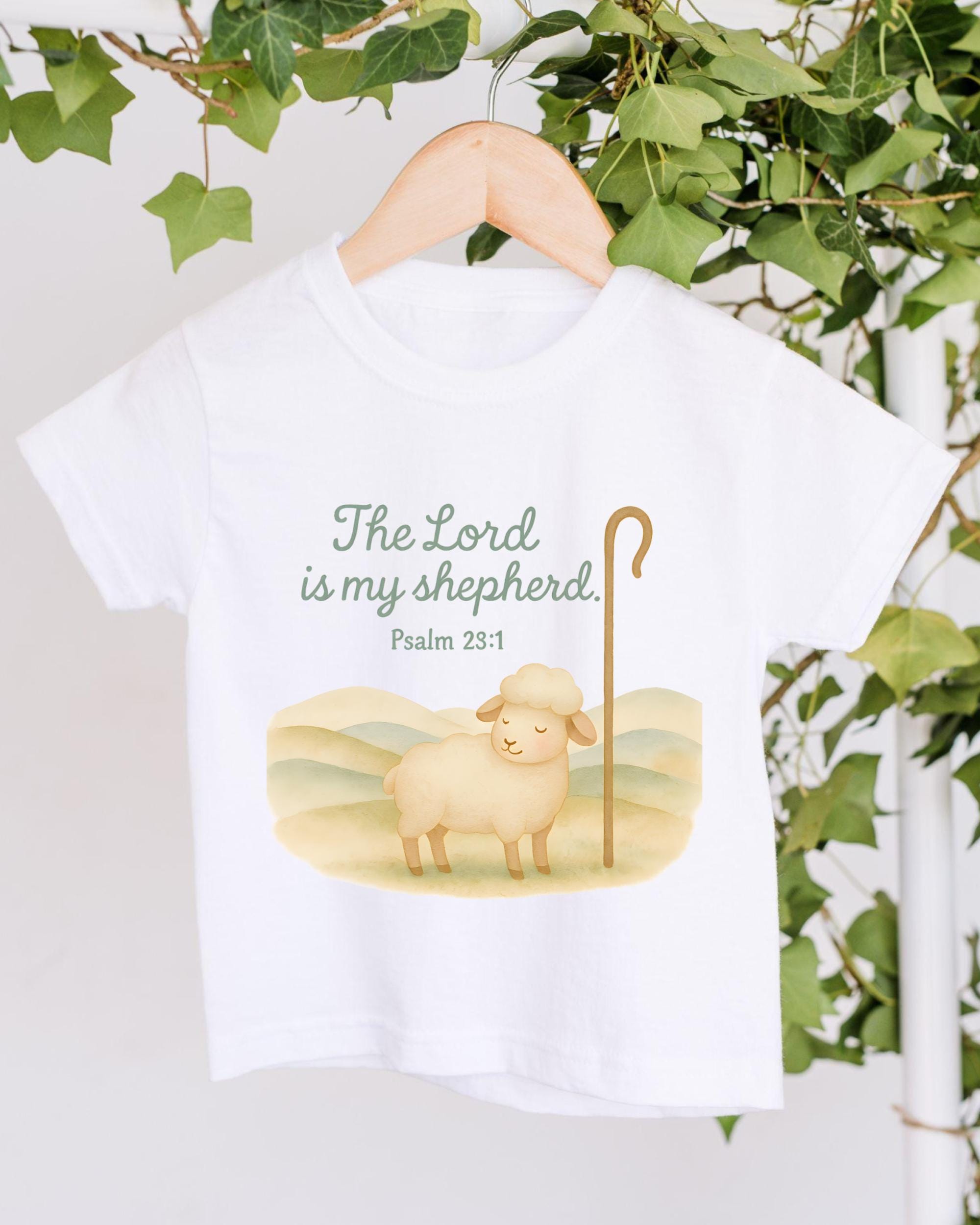 A white t-shirt with a printed design depicting a sheep and the text "The Lord is my shepherd. Psalm 23:1"