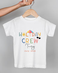 A white t-shirt with colorful text and graphics, including the words "HOLIDAY CREW" and "July 2023", suggesting a summer-themed design.