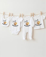 A collection of baby clothes, including onesies and bibs, hanging on a clothesline.