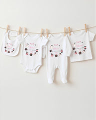 A row of four white baby clothes, including bibs and onesies, hanging on a clothesline.