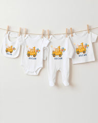 A collection of baby clothes, including onesies and bibs, are hanging on a clothesline.
