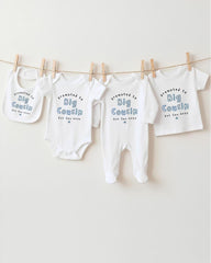 A row of four white baby clothes, including bibs and onesies, hanging on a clothesline.