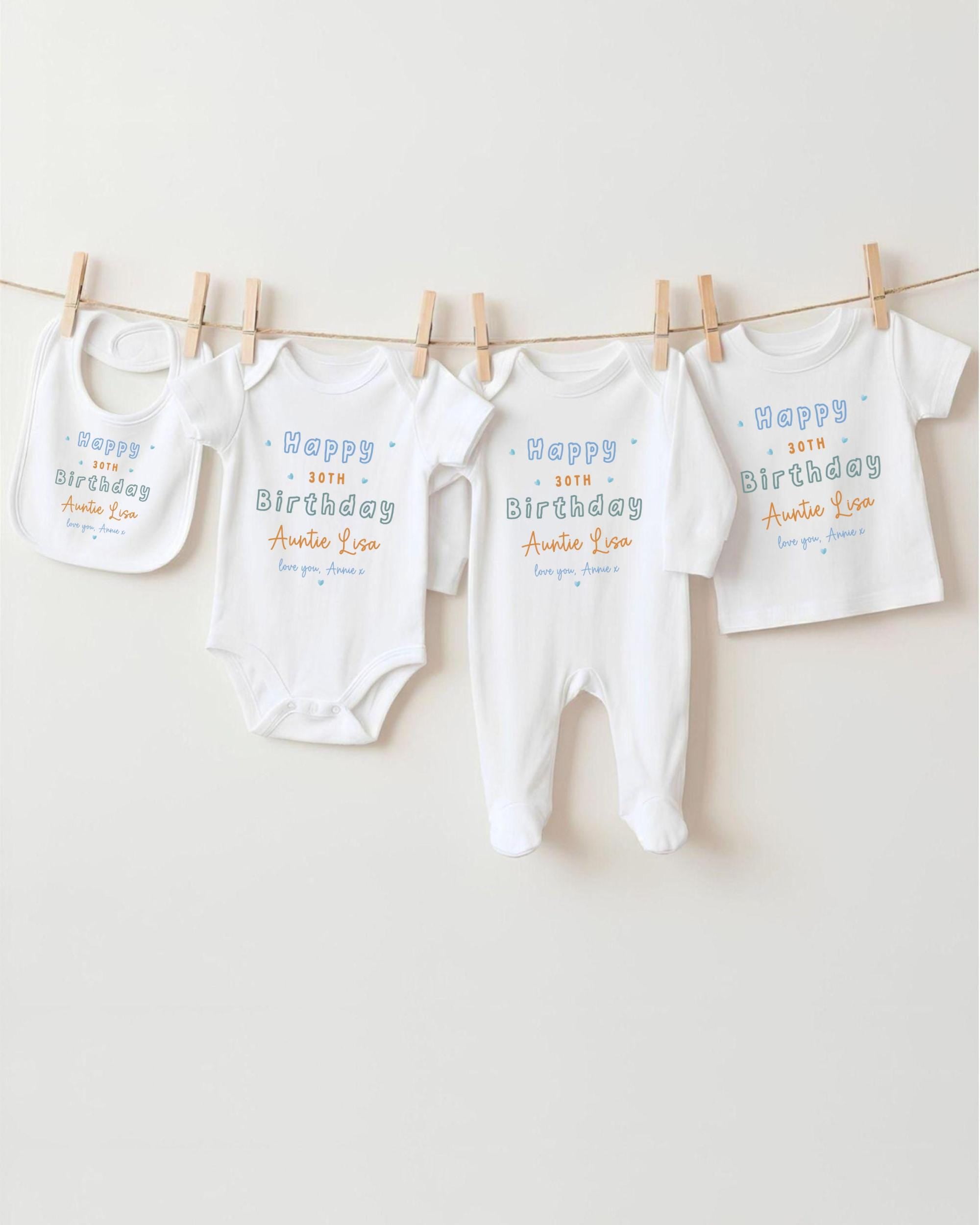 A row of white baby clothes, including onesies and bibs, hanging on a clothesline.