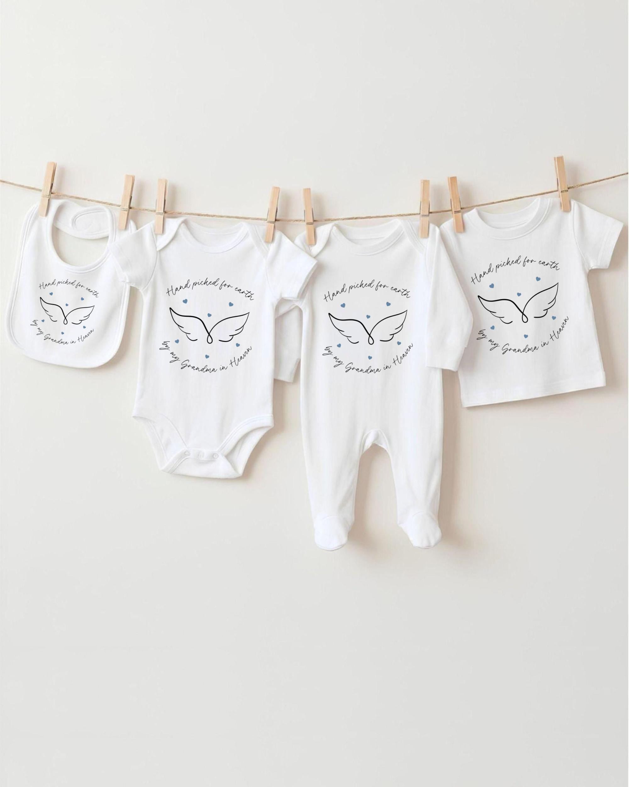 A row of four white baby clothes with a wing design, hanging on a clothesline.