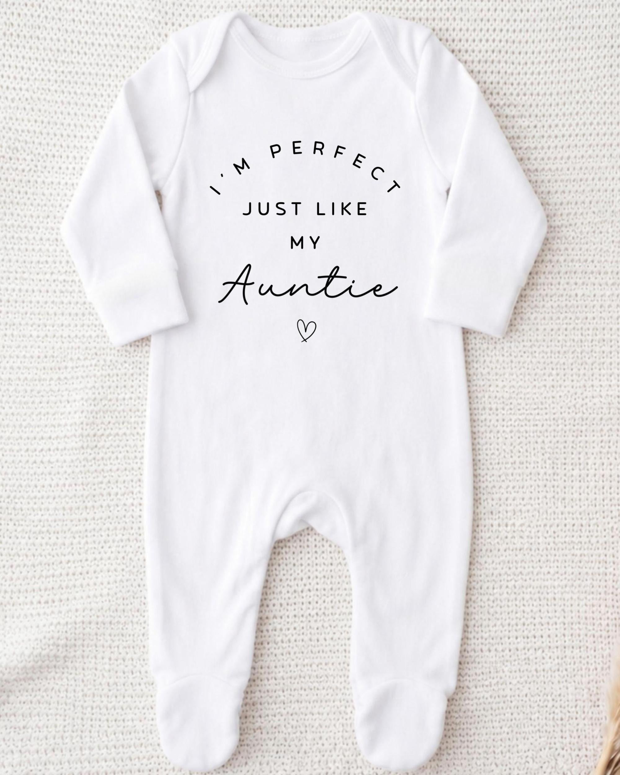 A white onesie with the text "I'M PERFECT JUST LIKE MY AUNTIE" printed on it.