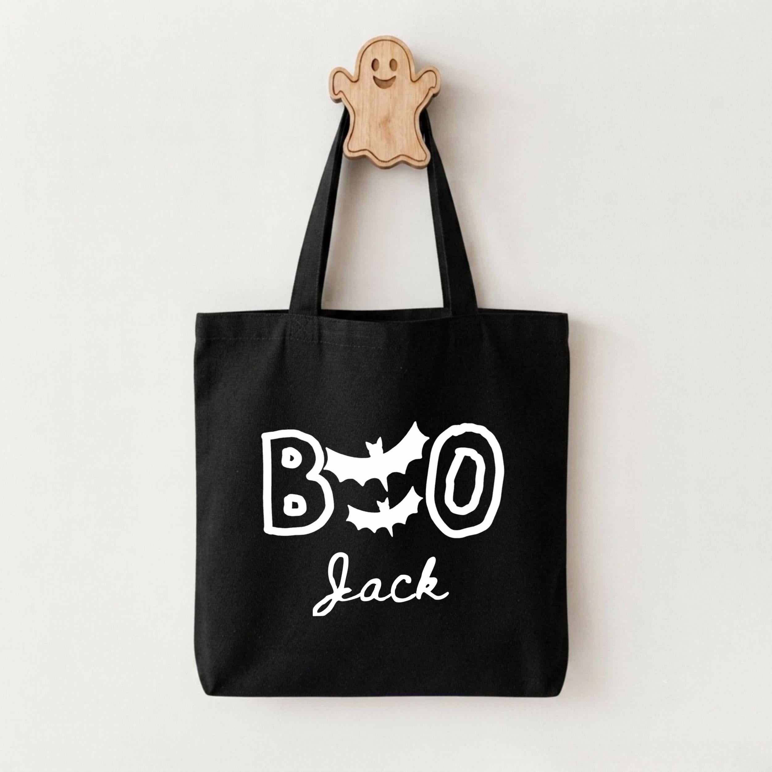 A black tote bag with the text "BOO Jack" printed on it, along with a ghost-shaped wooden hanger.