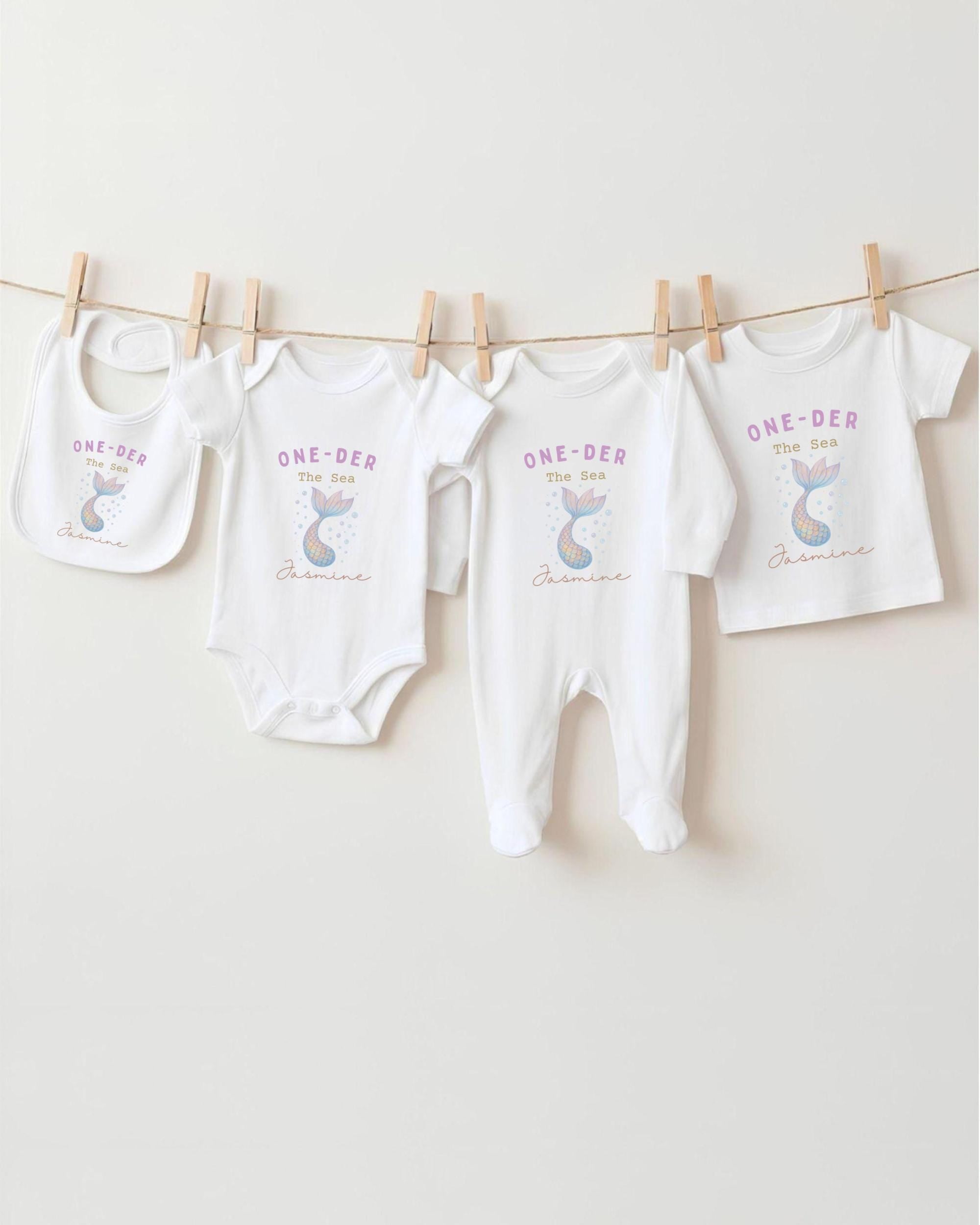 A collection of white baby clothes, including onesies and bibs, hanging on a clothesline.