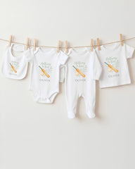 A collection of baby clothes, including onesies and bibs, hanging on a clothesline.