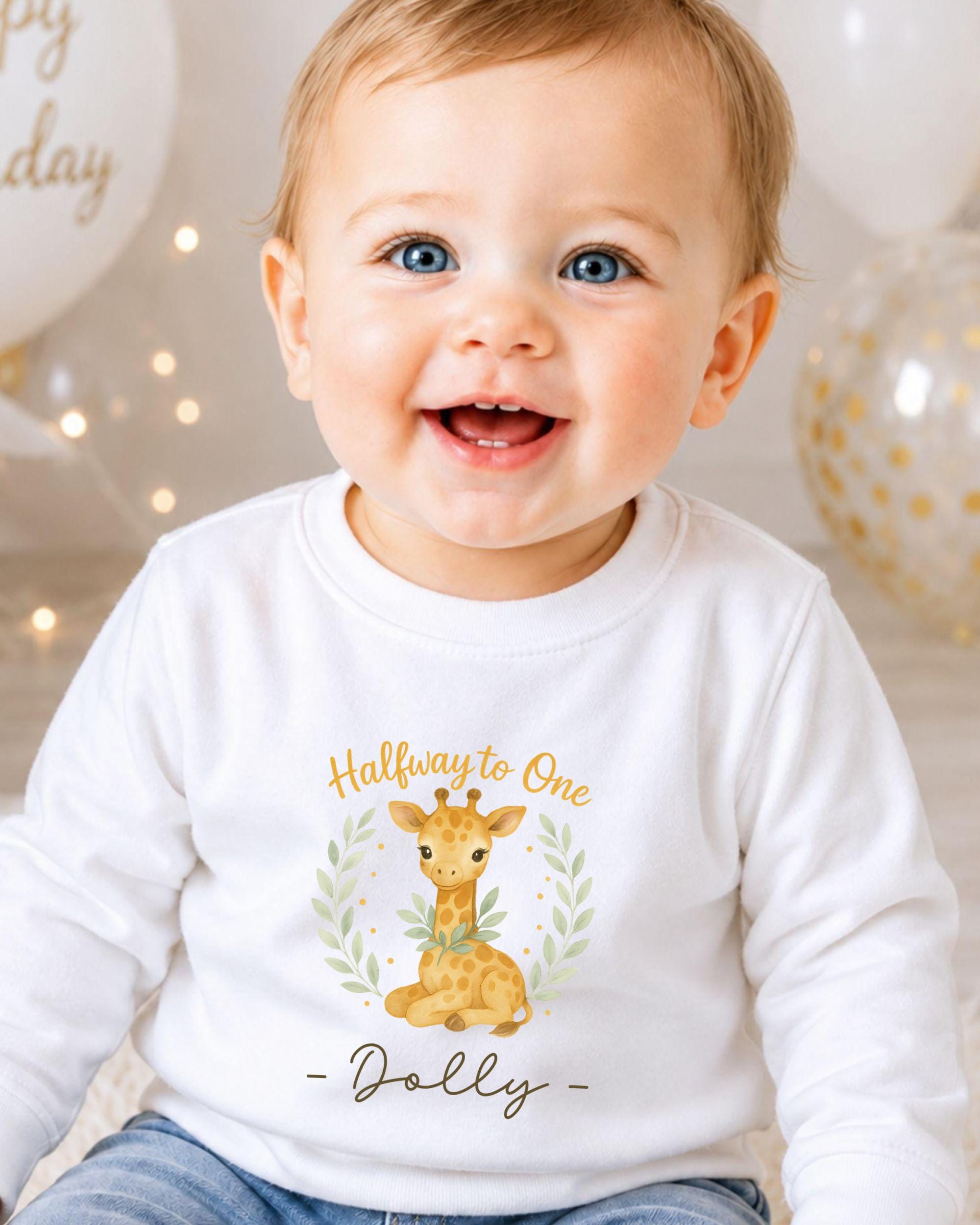 A smiling baby boy wearing a white shirt with a giraffe graphic and the text "Halfway to One - Dolly" printed on it.