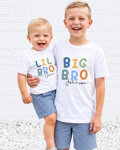 Two young boys wearing matching white t-shirts with the text "Lil Bro Johnson" printed on them, smiling and posing together.