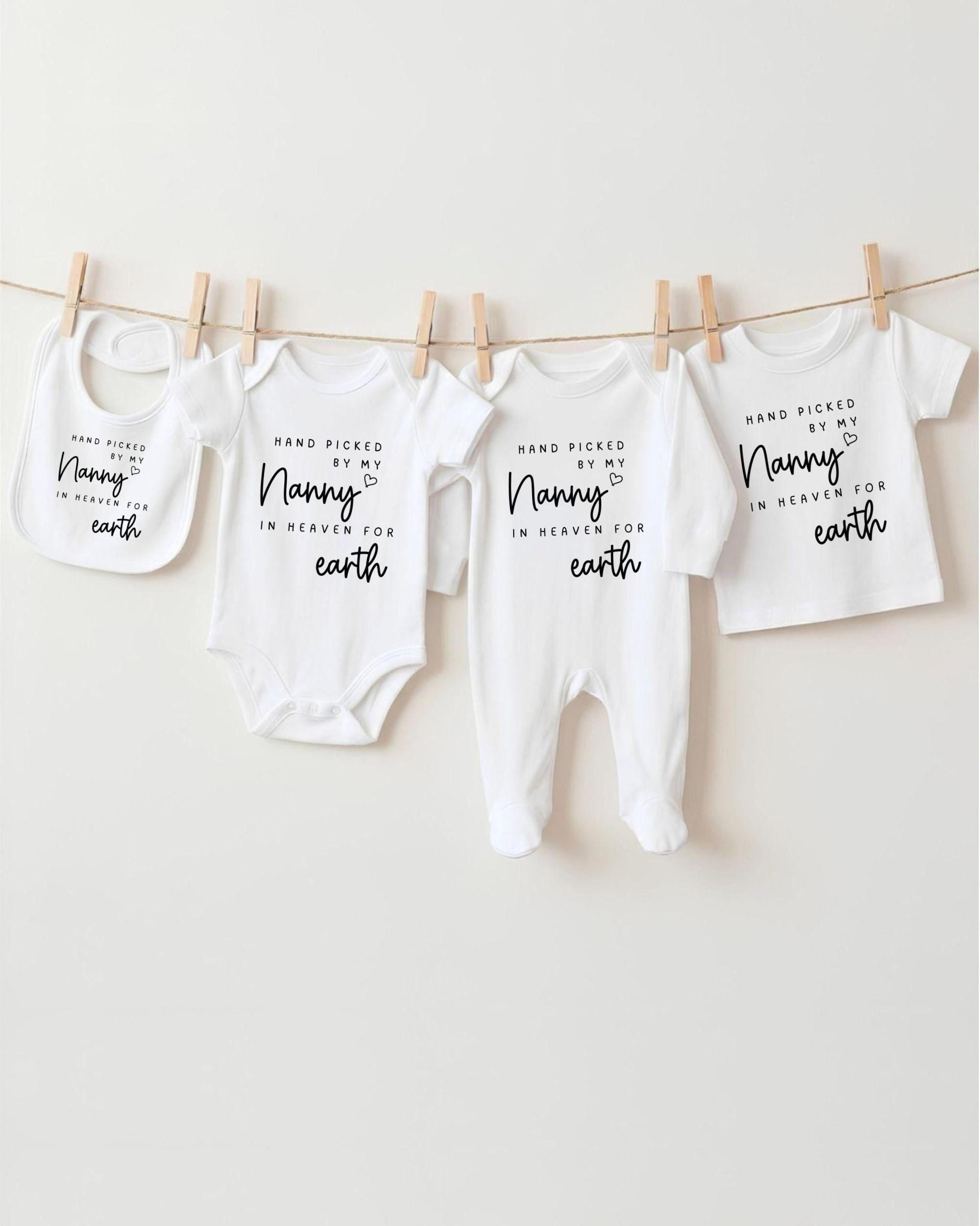 A row of four white baby clothes with black text, hanging on a clothesline.