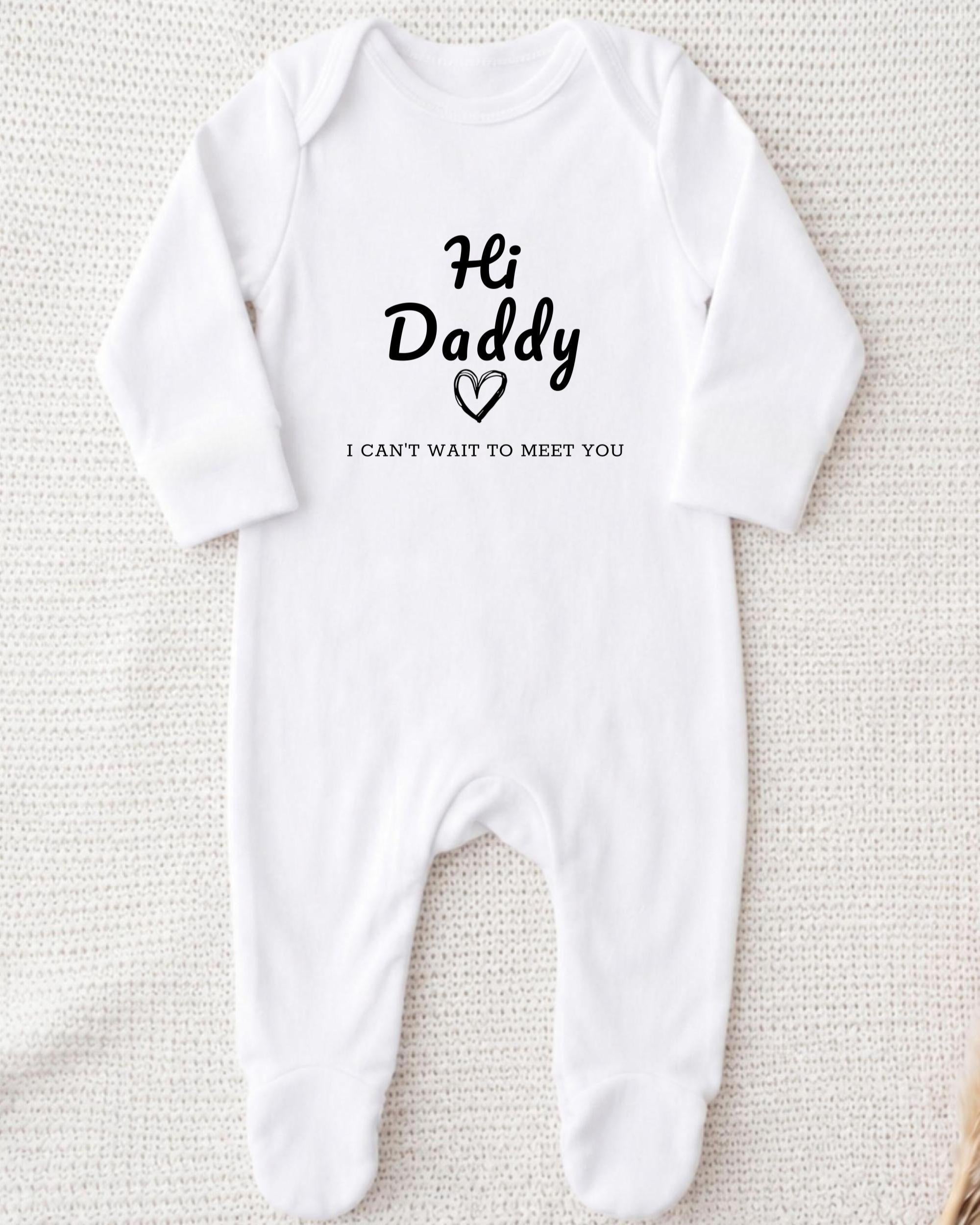 A white onesie with the text "Hi Daddy I can't wait to meet you" printed on it.