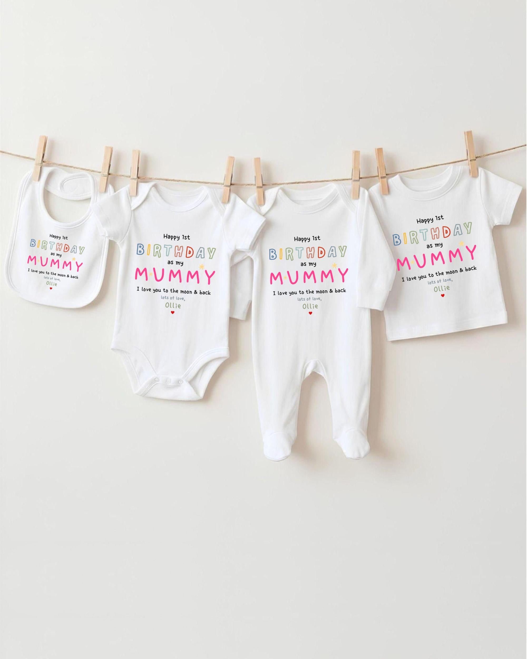 A row of four white baby clothes, including onesies and bibs, hanging on a clothesline.