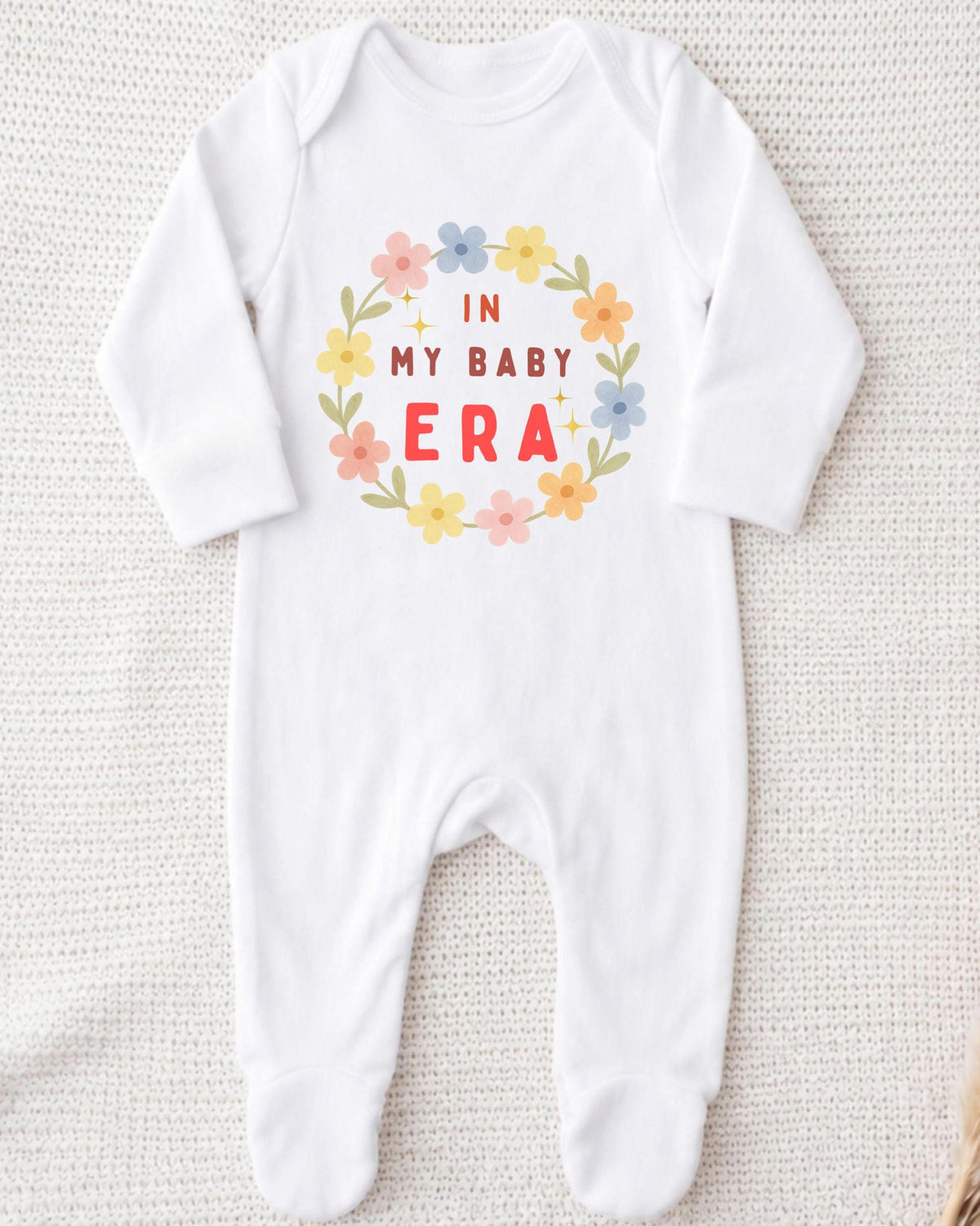 A white onesie with a floral design and text printed on it.