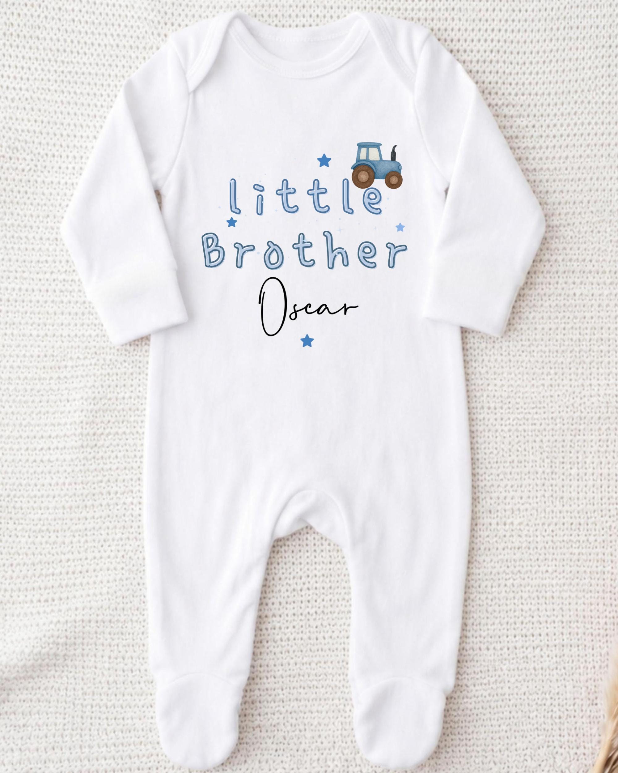 A white onesie with the text "Little Brother Oscar" printed on it, along with a small tractor graphic.