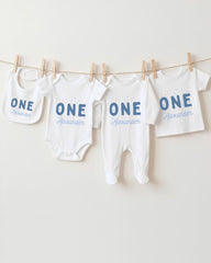 A row of four white baby clothes with the name "Alexander" printed on them, hanging on a clothesline.