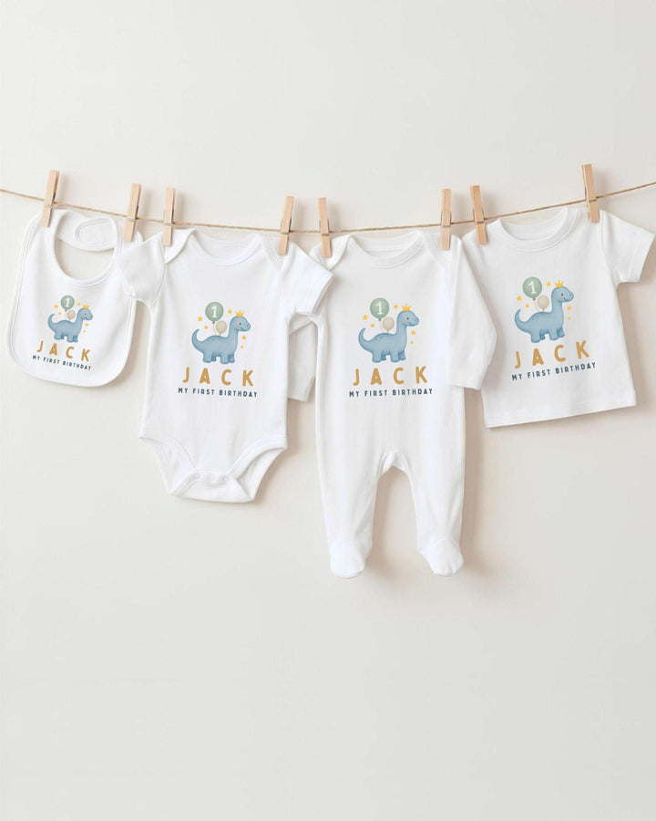 A collection of baby clothes, including bodysuits and bibs, hanging on a clothesline.