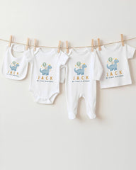 A collection of baby clothes, including onesies and bibs, hanging on a clothesline.
