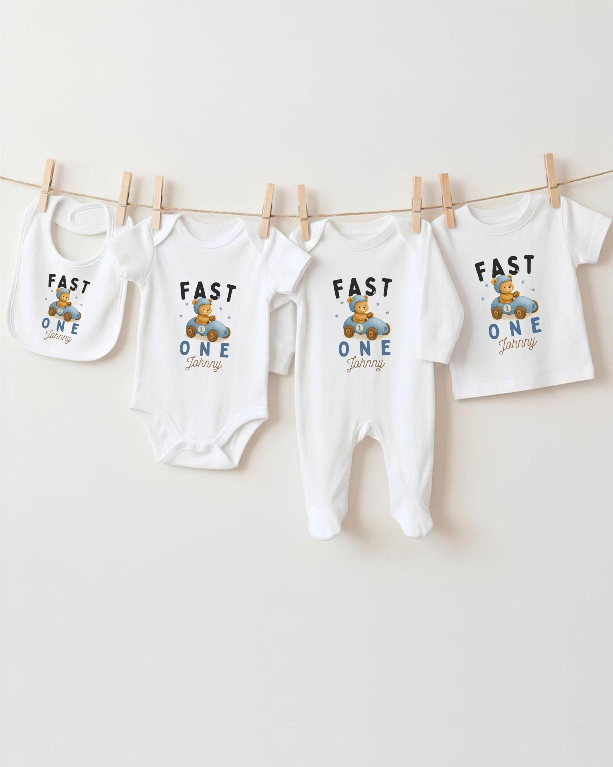 A collection of baby clothes, including onesies and bibs, hanging on a clothesline.