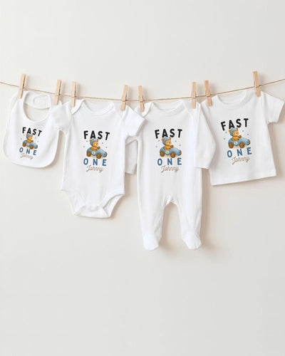 A collection of baby clothes, including bodysuits and bibs, hanging on a clothesline.