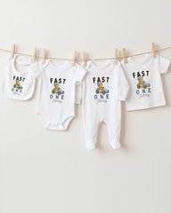 A collection of baby clothes, including onesies and bibs, hanging on a clothesline.