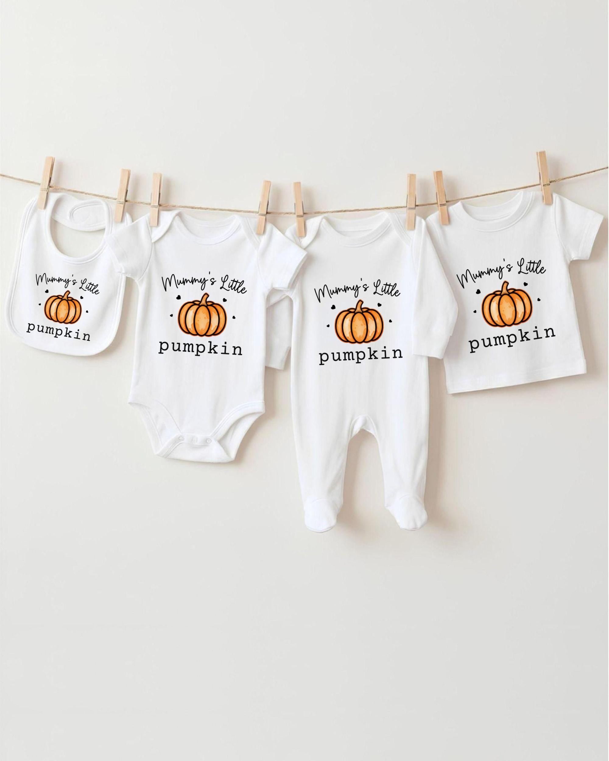 A row of four white baby clothes with pumpkin designs, each with the text "Mummy's Little pumpkin" printed on them.