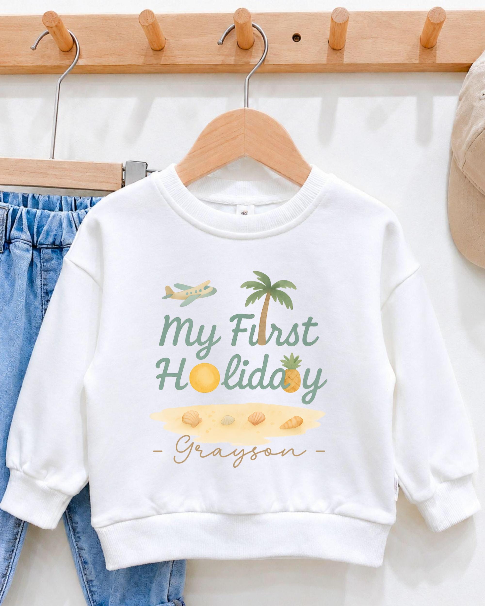A white sweatshirt with a graphic design and text printed on it, hanging on a wooden hanger.