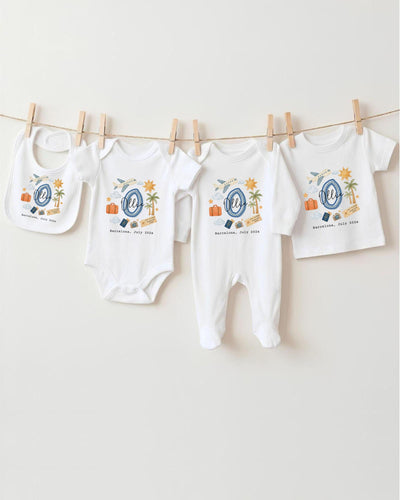 A collection of baby clothes, including onesies and bibs, hanging on a clothesline.
