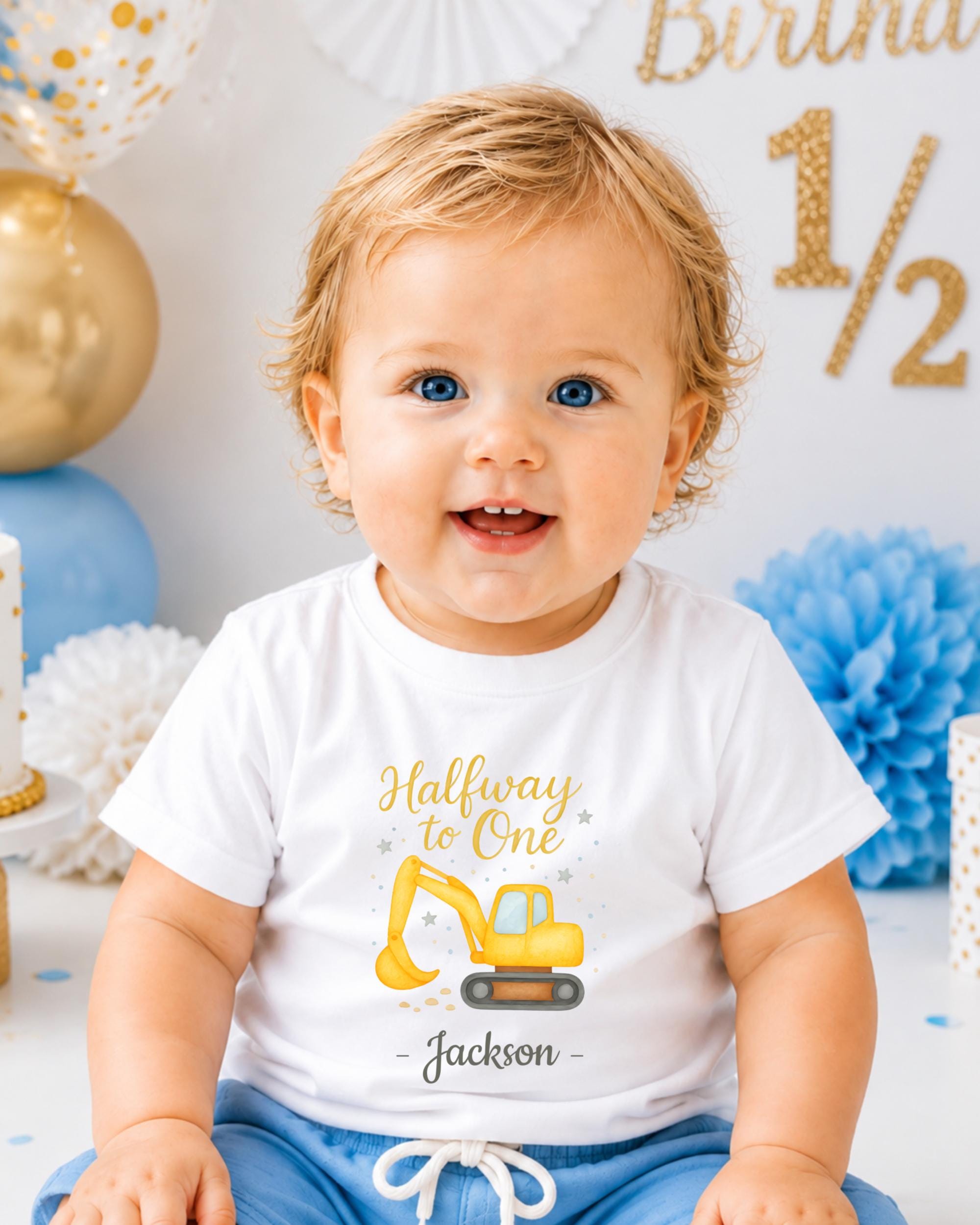 A smiling baby boy wearing a white t-shirt with a cartoon construction vehicle and the text "Halfway to One Jackson" printed on it.