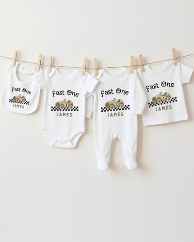 A collection of white baby clothes, including bodysuits and bibs, hanging on a clothesline.