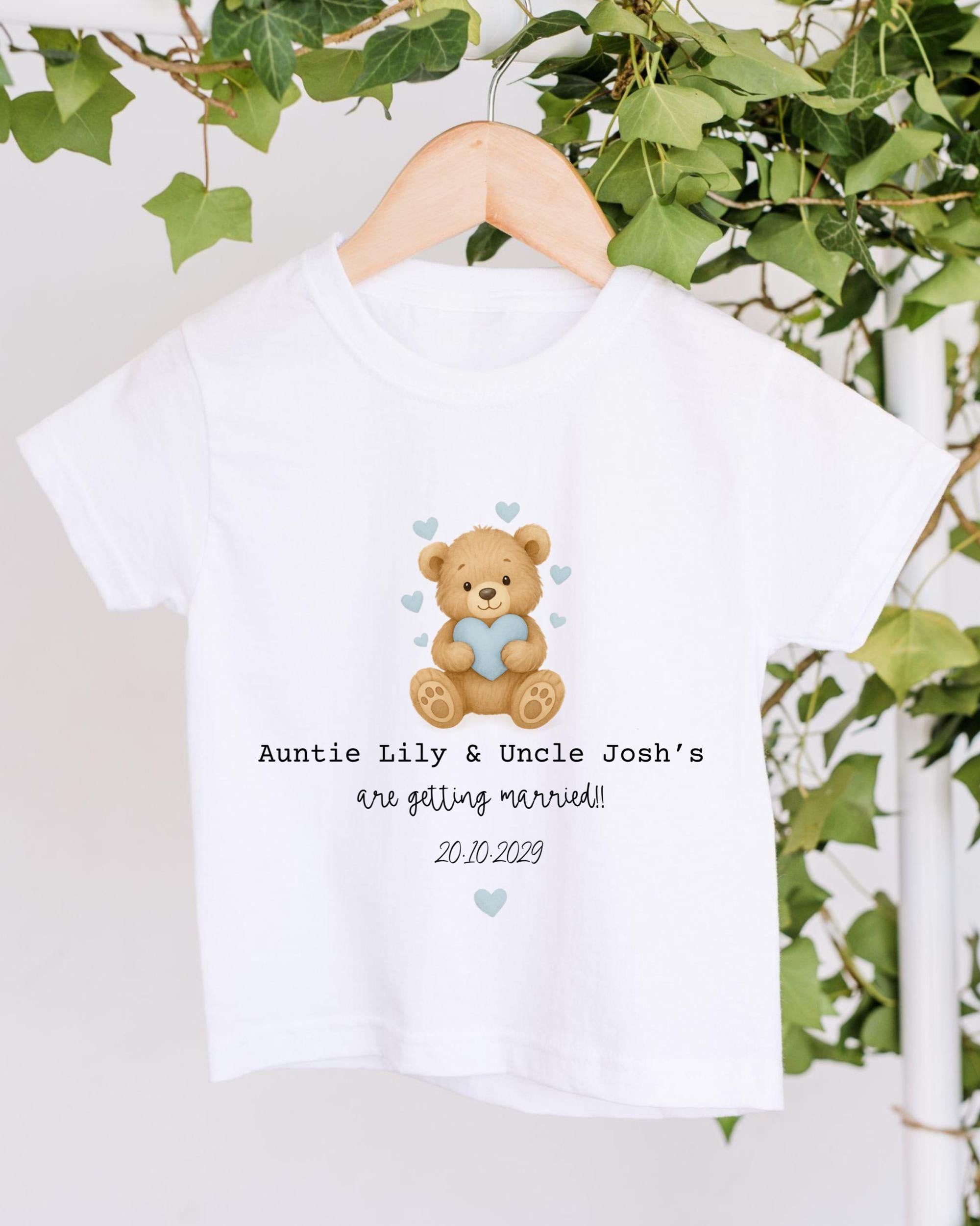 A white t-shirt with a teddy bear graphic and text that reads "Auntie Lily & Uncle Josh's are getting married! 20.10.2029".