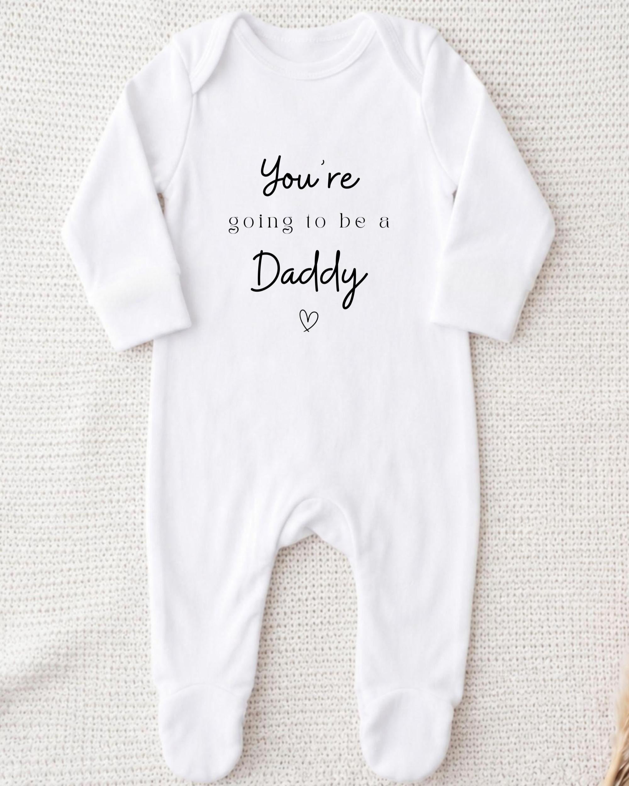 A white onesie with the text "You're going to be a Daddy" printed on it.