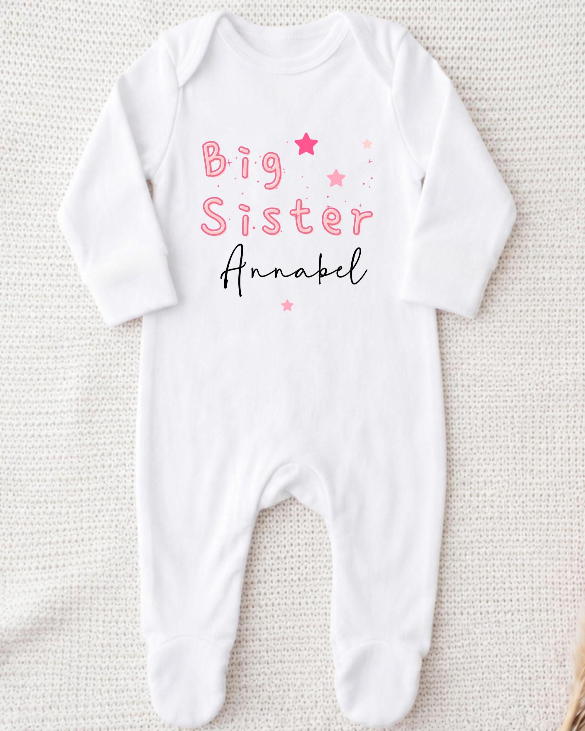 A white onesie with the text "Big Sister Annabel" printed on it.