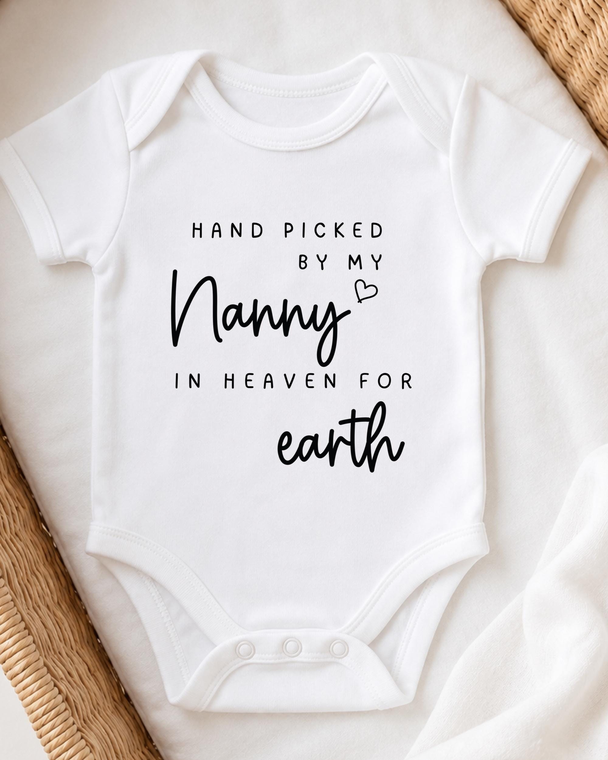 A white baby onesie with black text that reads "HAND PICKED BY MY NANNY IN HEAVEN FOR earth".