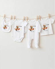 A collection of white baby clothes, including onesies and bibs, hanging on a clothesline.