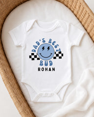 A white onesie with a blue smiley face and text printed on it, placed in a woven basket.