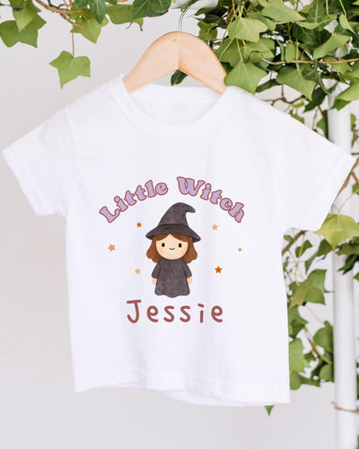 A white t-shirt with a cartoon image of a witch and the text "Little Witch Jessie" printed on it.