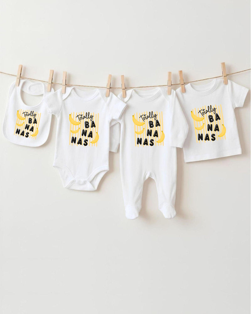 A collection of baby clothes, including onesies and bibs, hanging on a clothesline.