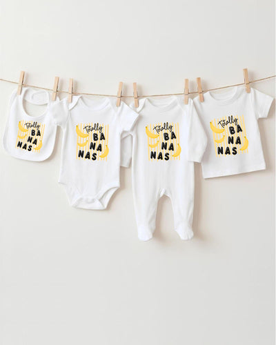 A collection of baby clothes, including onesies and bibs, hanging on a clothesline.