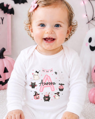 A smiling baby girl wearing a white bodysuit with a personalized name and Halloween-themed illustrations.