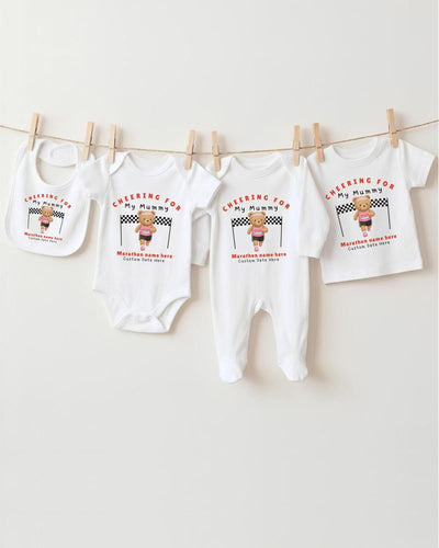 A collection of baby clothes, including onesies and bibs, hanging on a clothesline.