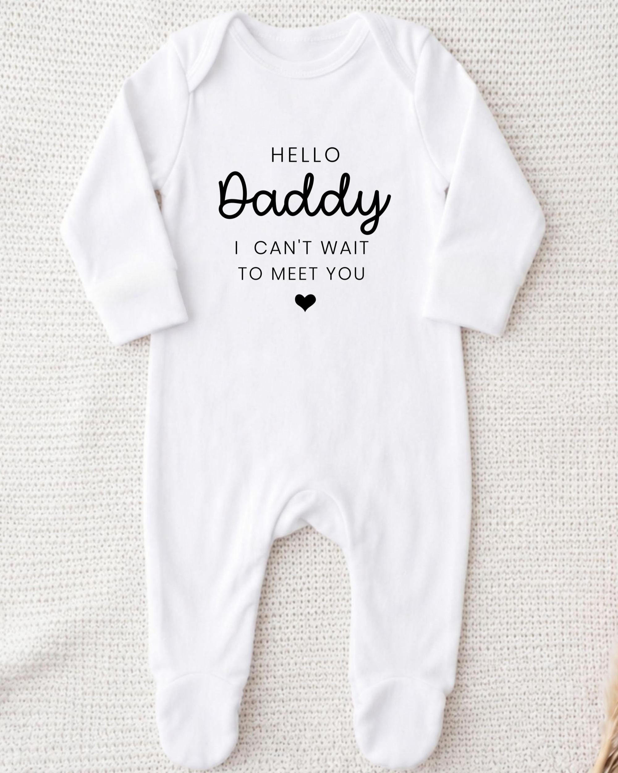 A white onesie with the text "Hello Daddy I can't wait to meet you" printed on it.