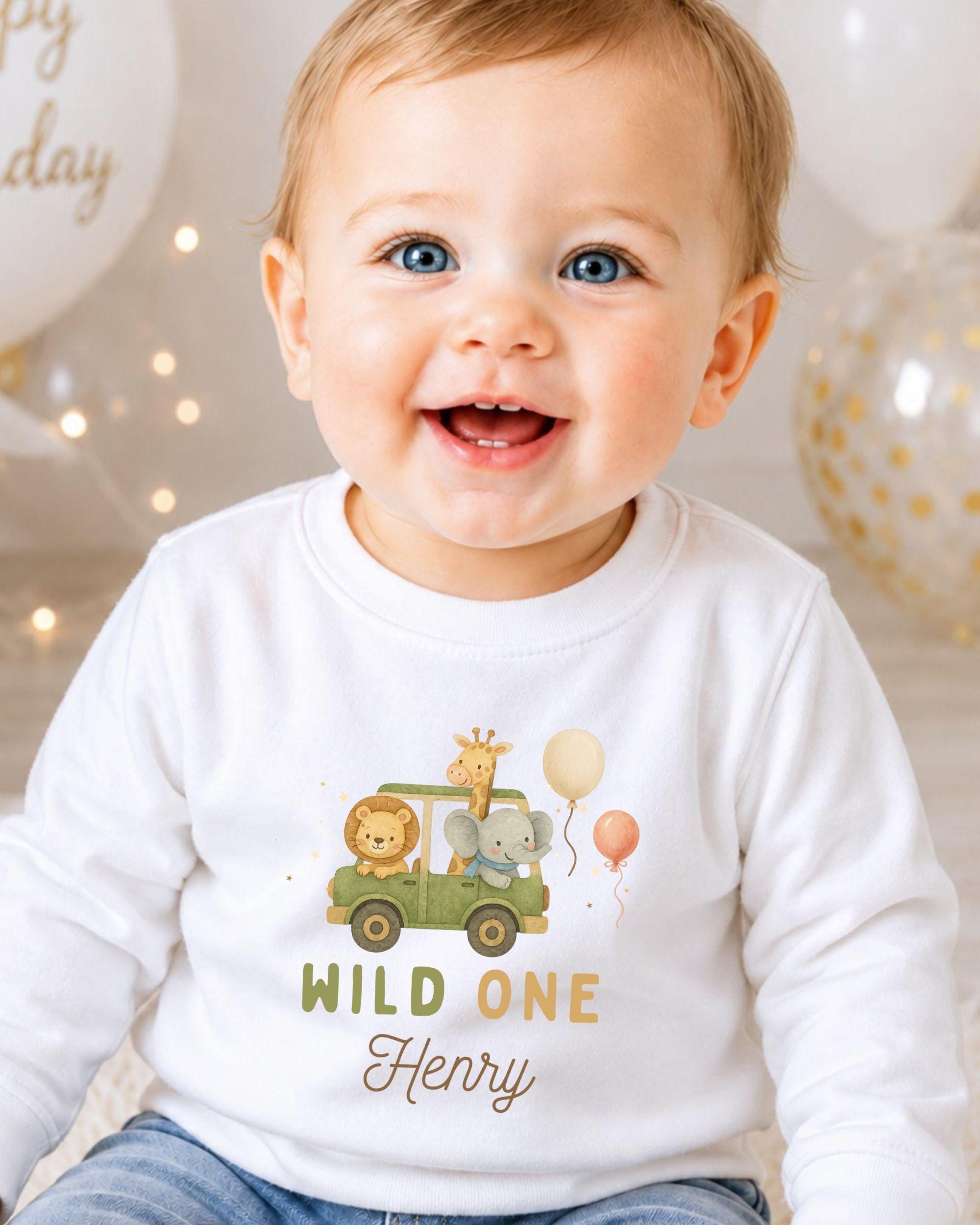 A smiling baby boy wearing a white shirt with a cartoon car and animals printed on it, with the text "WILD ONE Henry" printed below.
