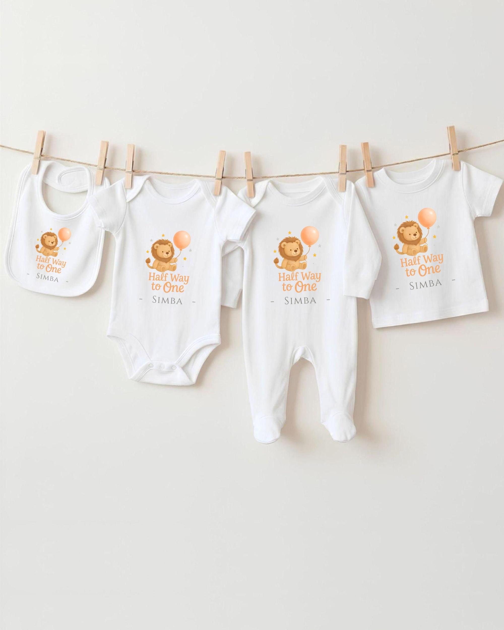 A collection of baby clothes, including onesies and bibs, hanging on a clothesline.