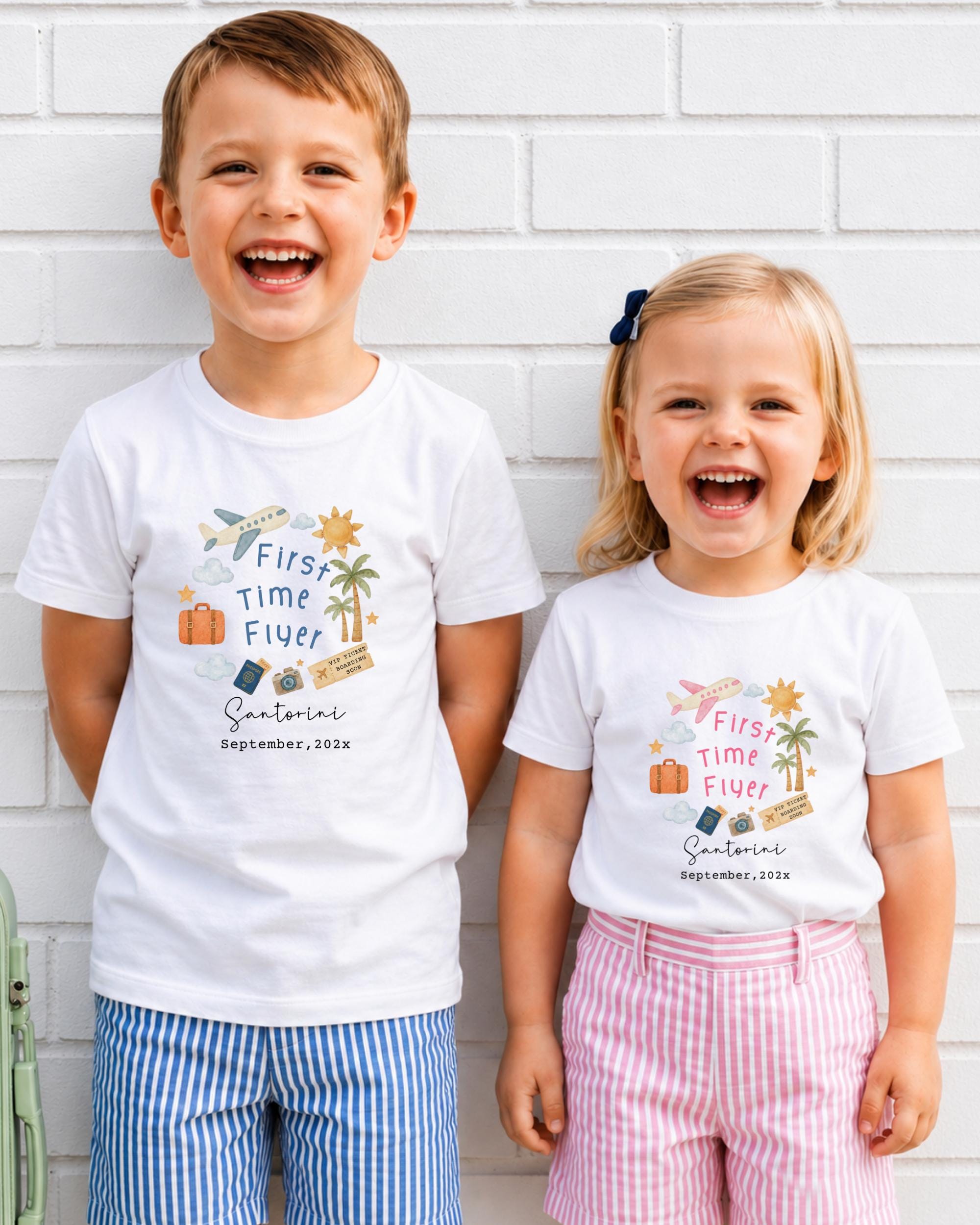 Two children, a boy and a girl, are standing next to each other and smiling, wearing matching white t-shirts with text and illustrations.