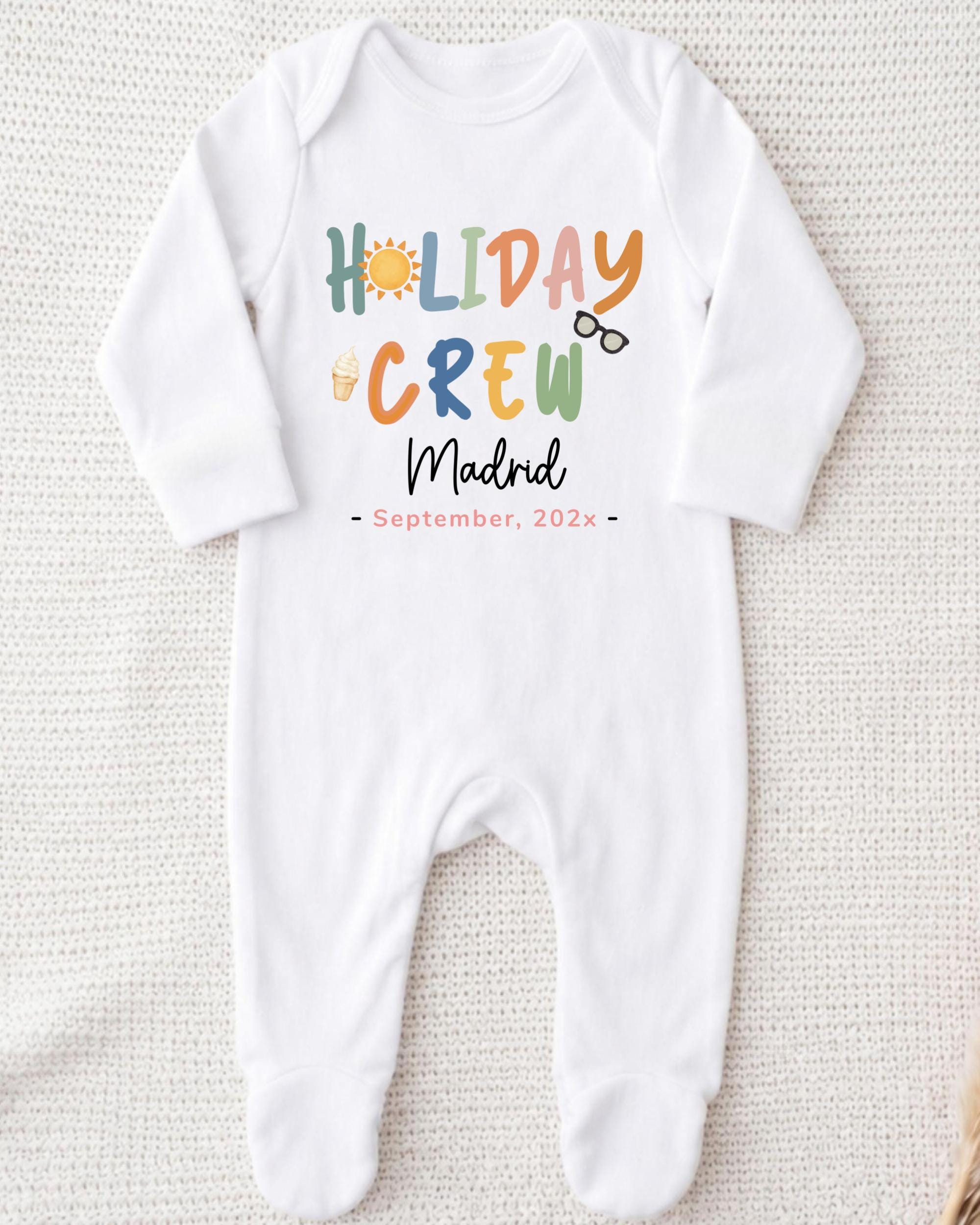 A white onesie with the text "HOLIDAY CREW MADRID September. 202x" printed on it.