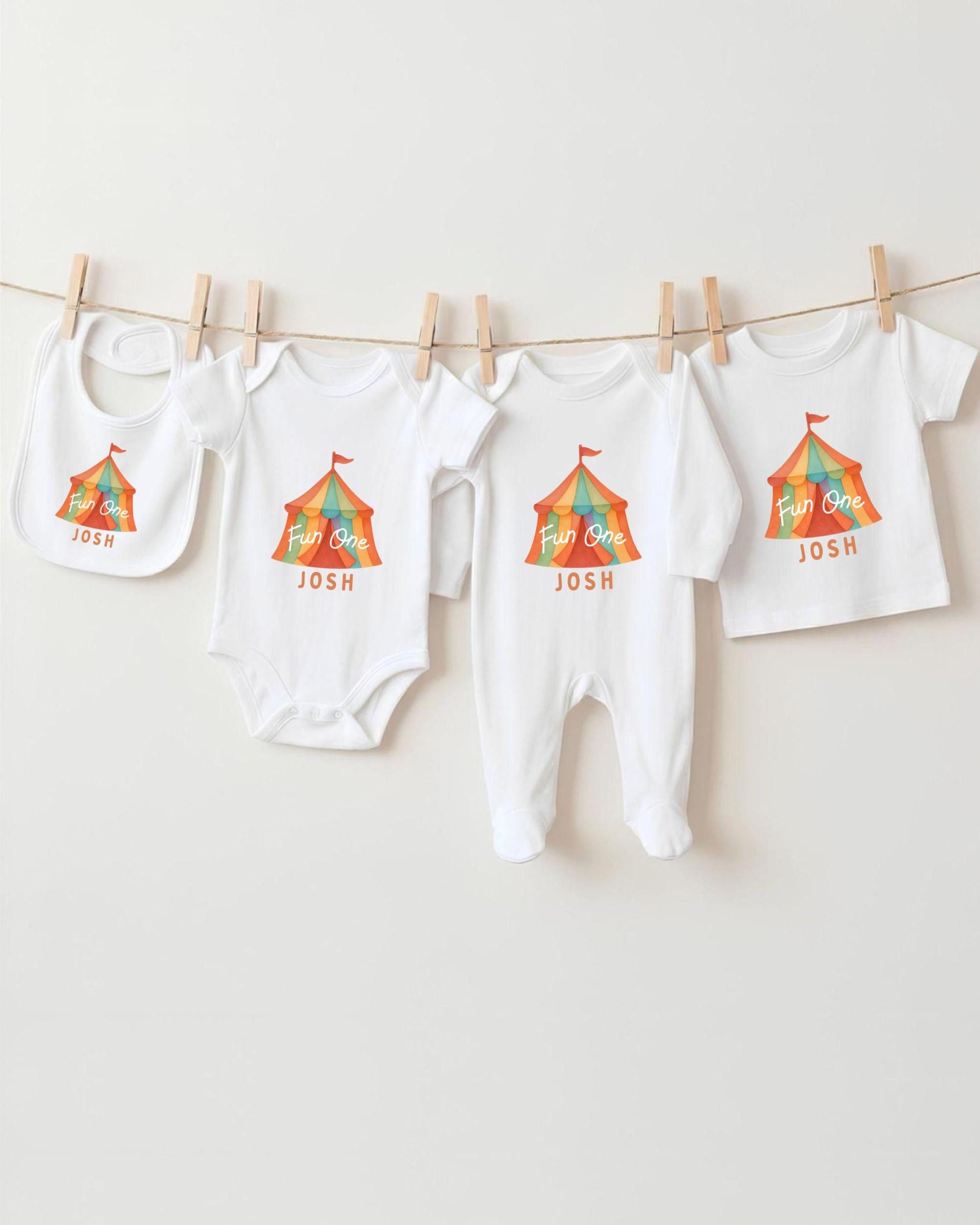 A collection of baby clothes, including onesies and bibs, hanging on a clothesline.