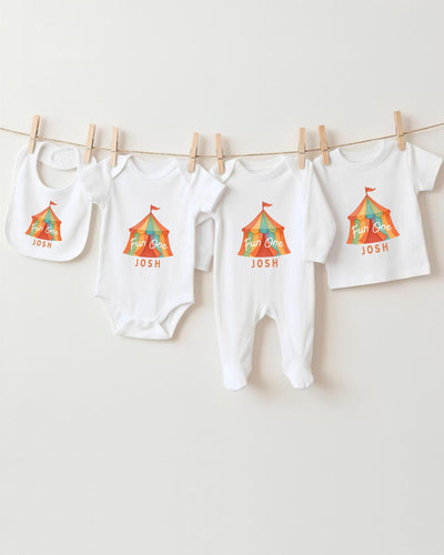 A collection of baby clothes, including bodysuits and bibs, hanging on a clothesline.