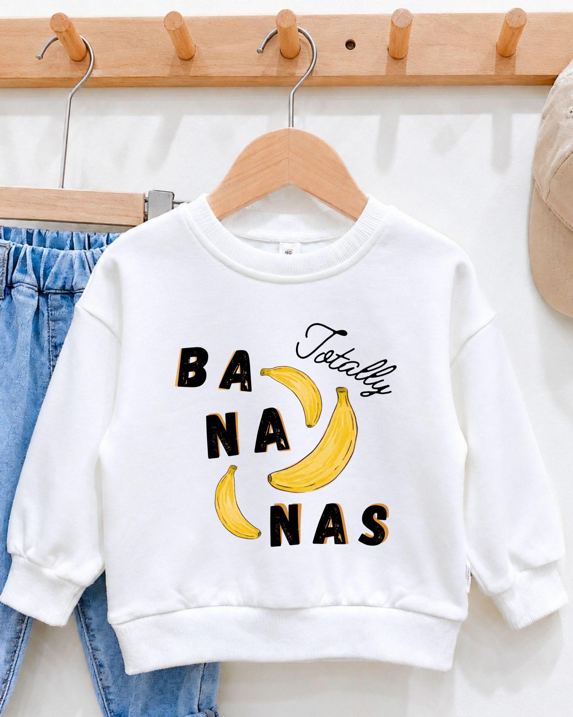 A white sweatshirt with a graphic design featuring bananas and the text " Totally bananas" printed on it.