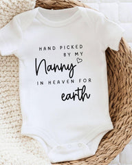 A white baby onesie with black text that reads "Hand picked by my Nanny in heaven for earth".